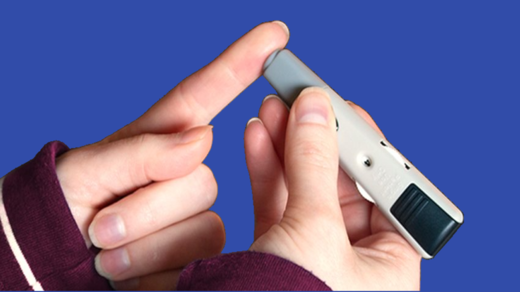 A picture containing someone holding a glucometer a lancet to the side of the finger.